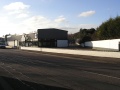 The view of the railway route looking towards Narroways Hill. The triangular shape of the wall and fence at the right of the car showroom gives away the route the railway took.