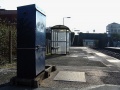 Looking along the platform with electrical boxes and shelters in view.