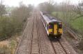 The view east from Wick Road bridge with a Scotrail liveried 150264 heading for Weston Super Mare. The railings either side of the train mark the spot where Balls Yeo Rhyne crosses under the railway.